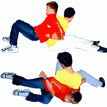 Zwei Kinder haken sich Rücken an Rücken sitzend mit den Armen ein und versuchen den Gegner umzudrehen.